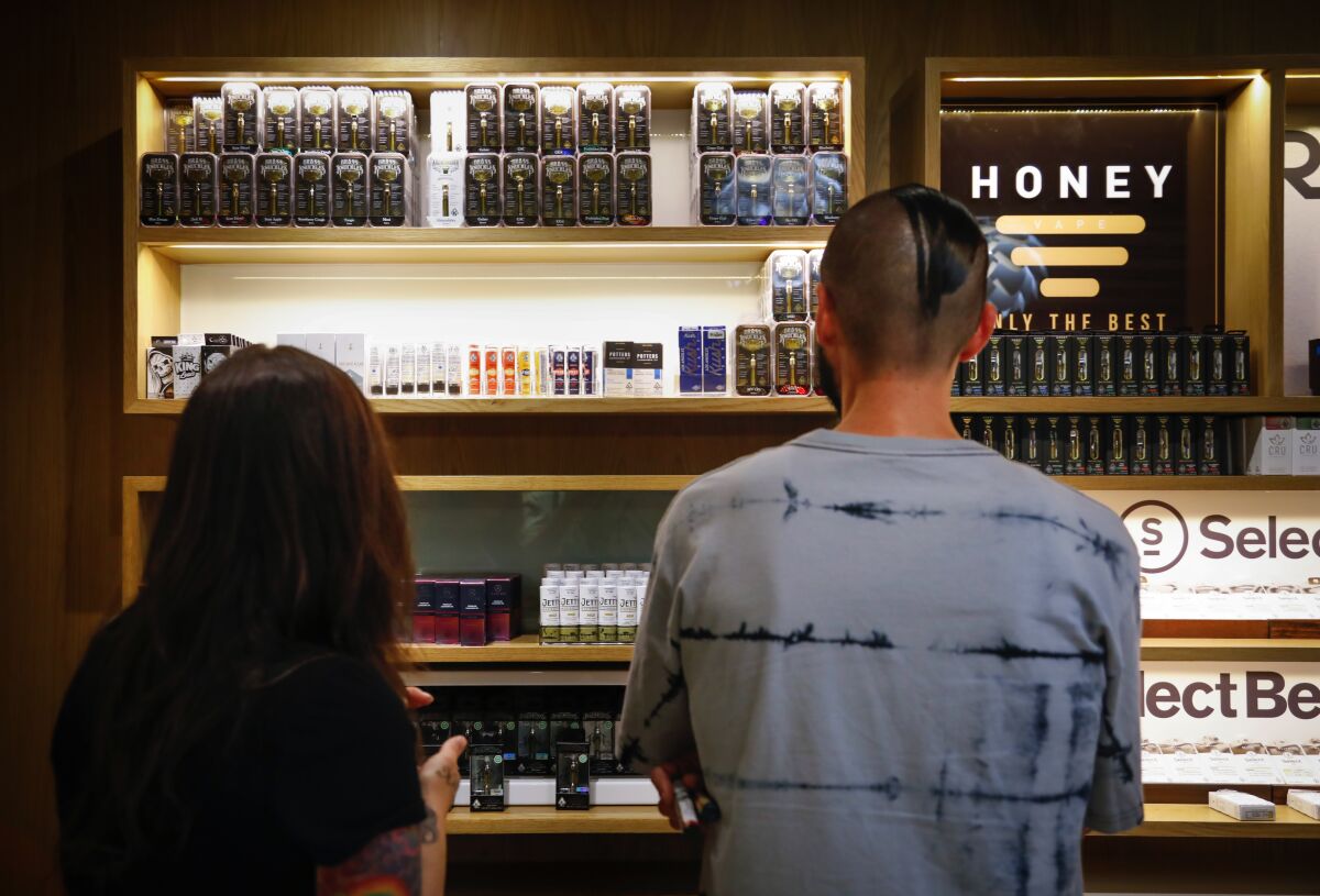 Tina Glen (left) and Nick Isordia look at the vaping products at March and Ash, a cannabis dispensary in Mission Valley.