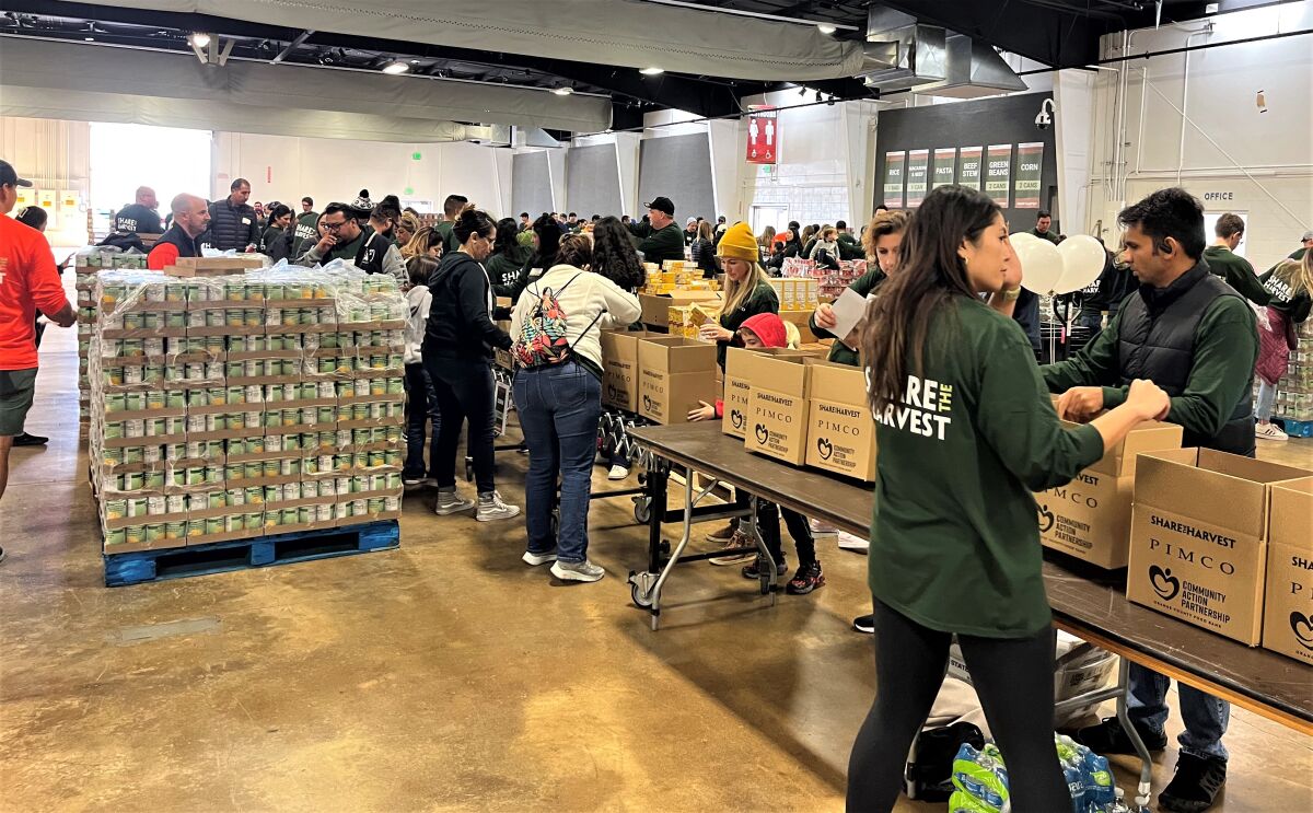 Employees of PIMCO at the O.C. fairgrounds package boxes of food and items for families.