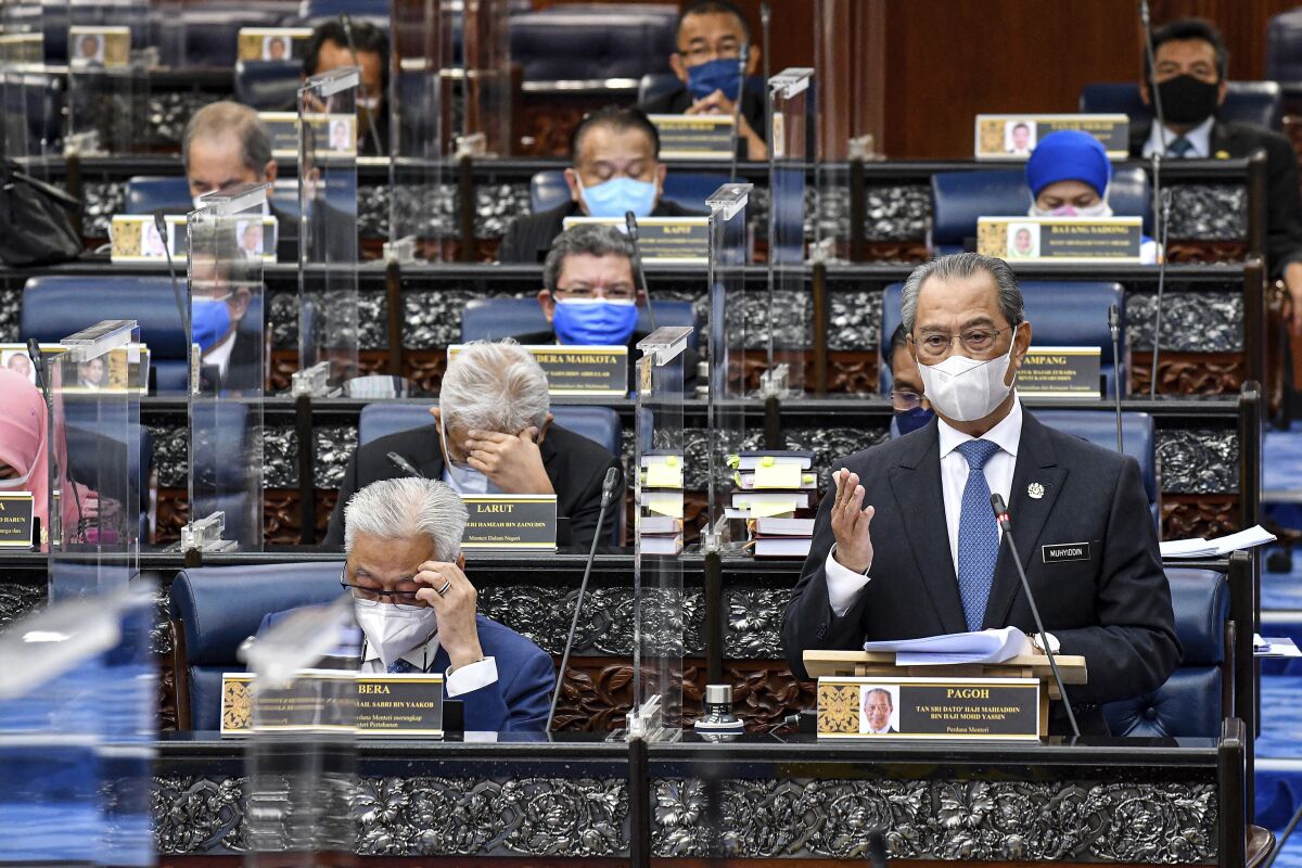In this photo released by Malaysia's Department of Information, Malaysia's Prime Minister Muhyiddin Yassin wearing a face mask to help curb the spread of the coronavirus speaks at the parliamentary session at parliament house in Kuala Lumpur, Monday, July 26, 2021. Malaysia's government said it will not extend a coronavirus emergency beyond August 1 as Parliament reopened Monday after a disputed seven-month suspension amid a worsening pandemic. (Famer Roheni/ Malaysia's Department of Information via AP)