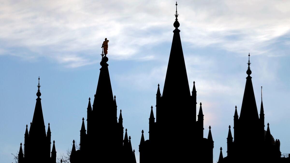 The angel Moroni statue, silhouetted against the sky atop spire second from left, stands atop the Salt Lake Temple, at Temple Squa