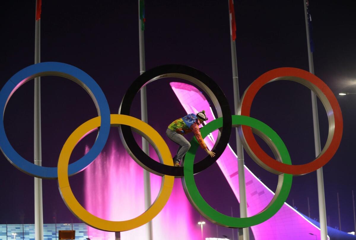 A volunteer climbs along the Olympic Rings during the closing ceremony of the Winter Games on Sunday at Fisht Olympic Stadium.