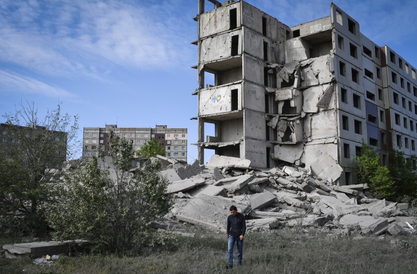 A man walks in front of a building destroyed by shelling in Ukraine.