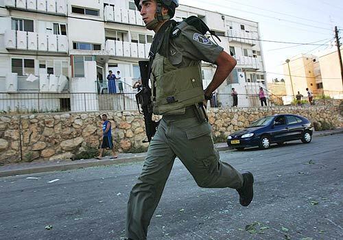 An Israeli soldier runs to the scene of a Katyusha rocket attack in a residential neighborhood in Kiryat Shmona in northern Israel. The adjacent multi-story apartment complex was damaged and a few residents were treated for minor injuries and trauma. Around 30 rockets were reported to have landed in Kiryat Shmona today.