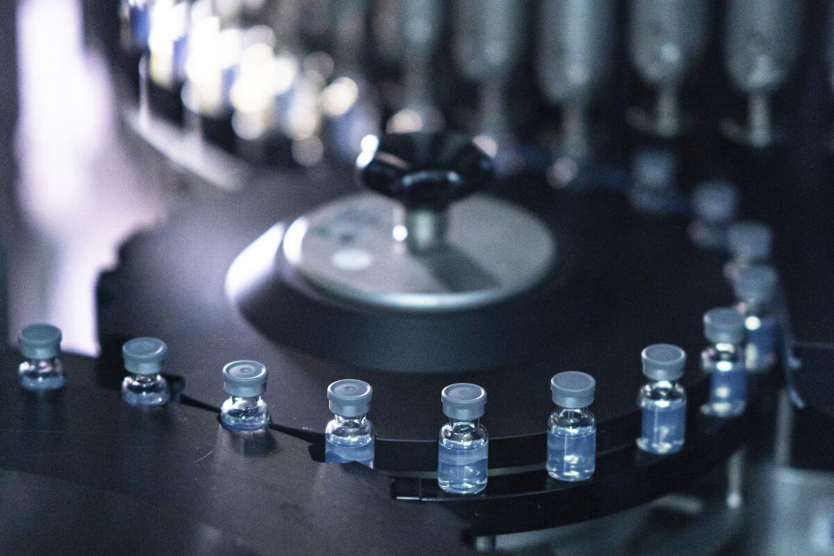 A line of vials with liquid inside snakes around metal wheels.