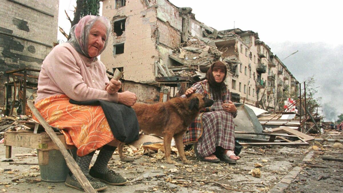 Two women beg for money on the rubble-strewn streets in the center of Grozny in August 1996.