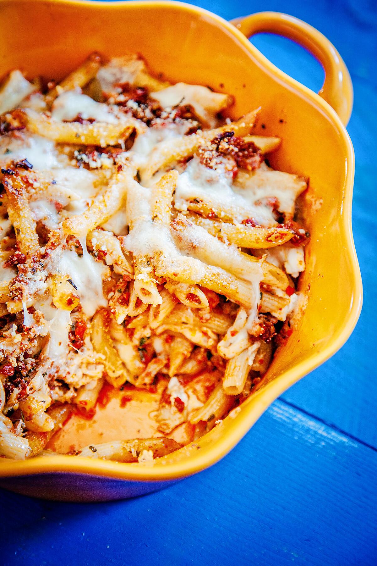 A baked pasta dish is studded with chicken, cheese and pine nuts.