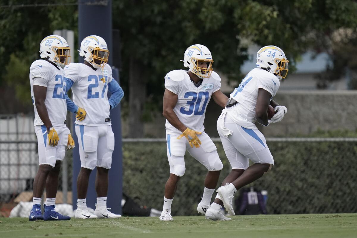 Austin Ekeler (30) hands the ball to fellow Chargers running back Darius Bradwell during practice Aug. 17 in Costa Mesa.