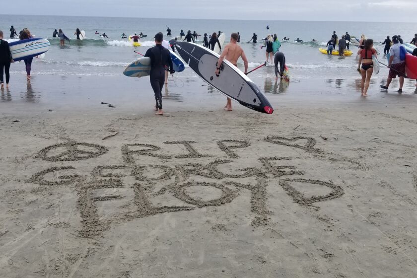 "RIP George Floyd" is written in the sand, while community members participate in Paddle Out at La Jolla Shores.