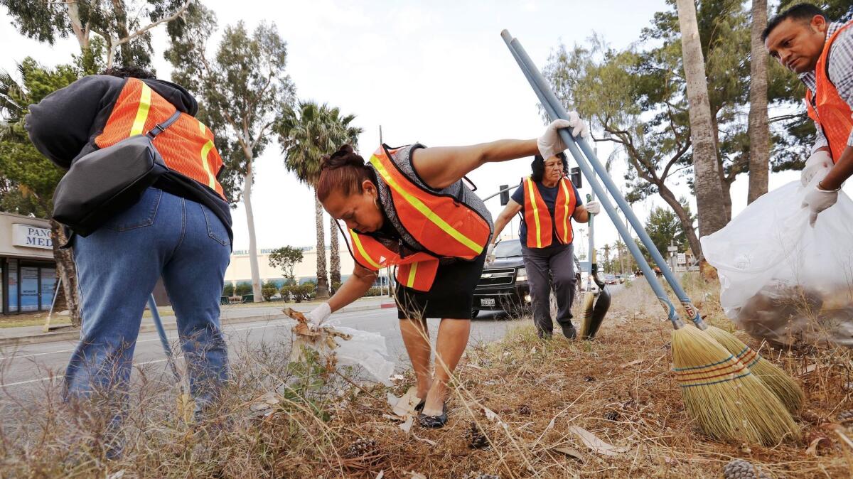 Street vendors from left, Rosa Alaman, Carmen Jimenez and Eloy Hernandez, clean the street median at the intersection of Tobias Avenue & Parthenia Street in Panorama City.