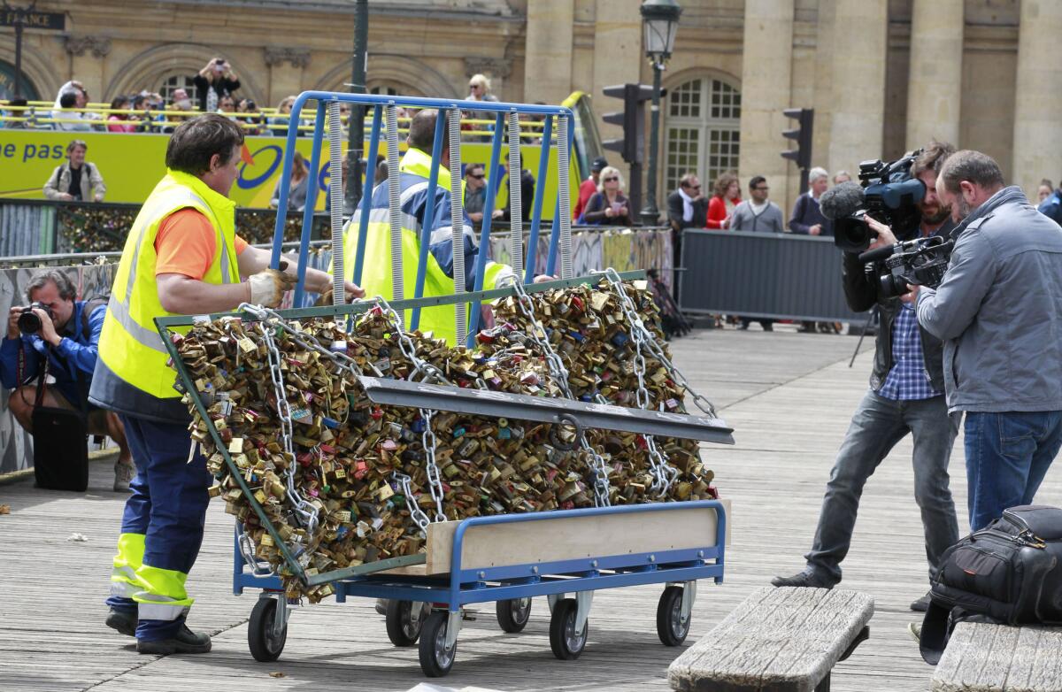 A Paris city employee removes a railing loaded with locks on the Pont des Arts in Paris.