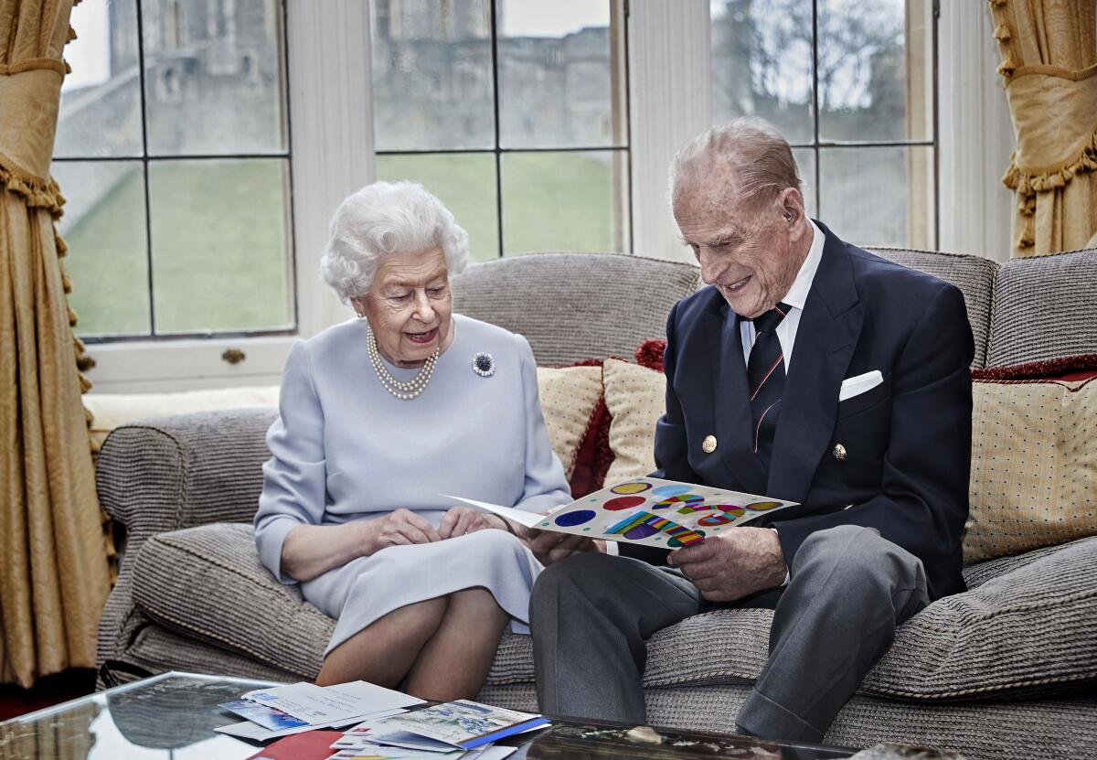  la reina Isabel II y el príncipe Felipe leen una tarjeta de aniversario de parte de sus bisnietos,