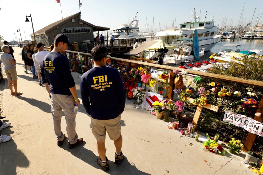 Al Seib  Los Angeles Times Members of an FBI dive team look at a growing memorial to the victims of the fire aboard the Conception, a dive boat that was anchored off Santa Cruz Island.
