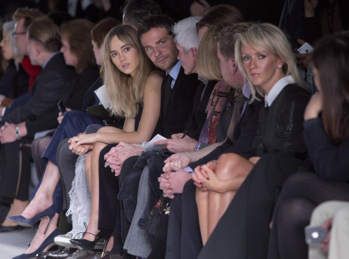 British model Suki Waterhouse, center left, sits next to her boyfriend Bradley Cooper as they watch Tom Ford's London Fashion Week show.