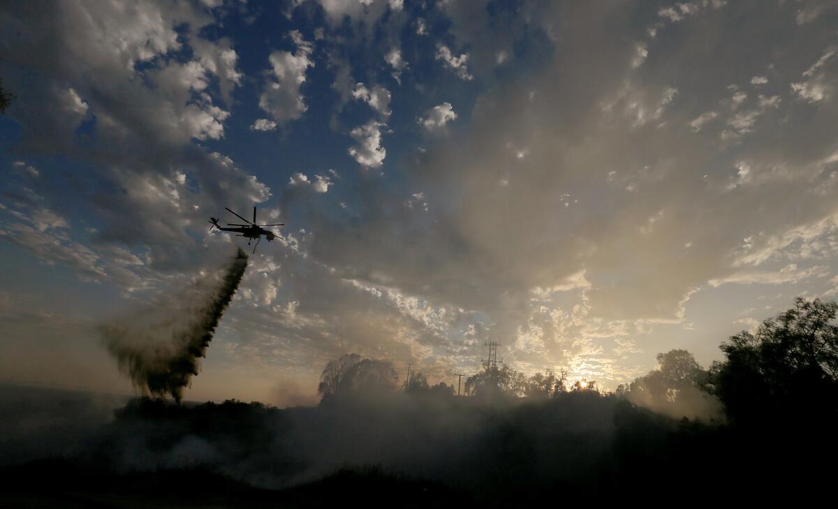 A helicopter makes a water drop on an 80 acre brush fire burning in the hills around Idaho Street in La Habra.