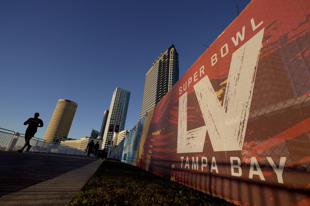 A man passes signage for Super Bowl 55