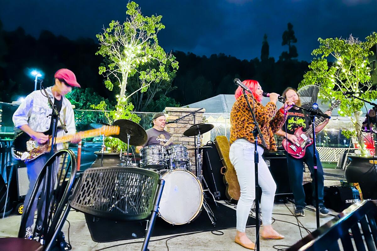 A woman sings with a band at night on an outdoor stage.