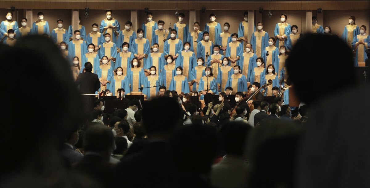 Choir members in blue and gold robes wear face masks during a church service in South Korea