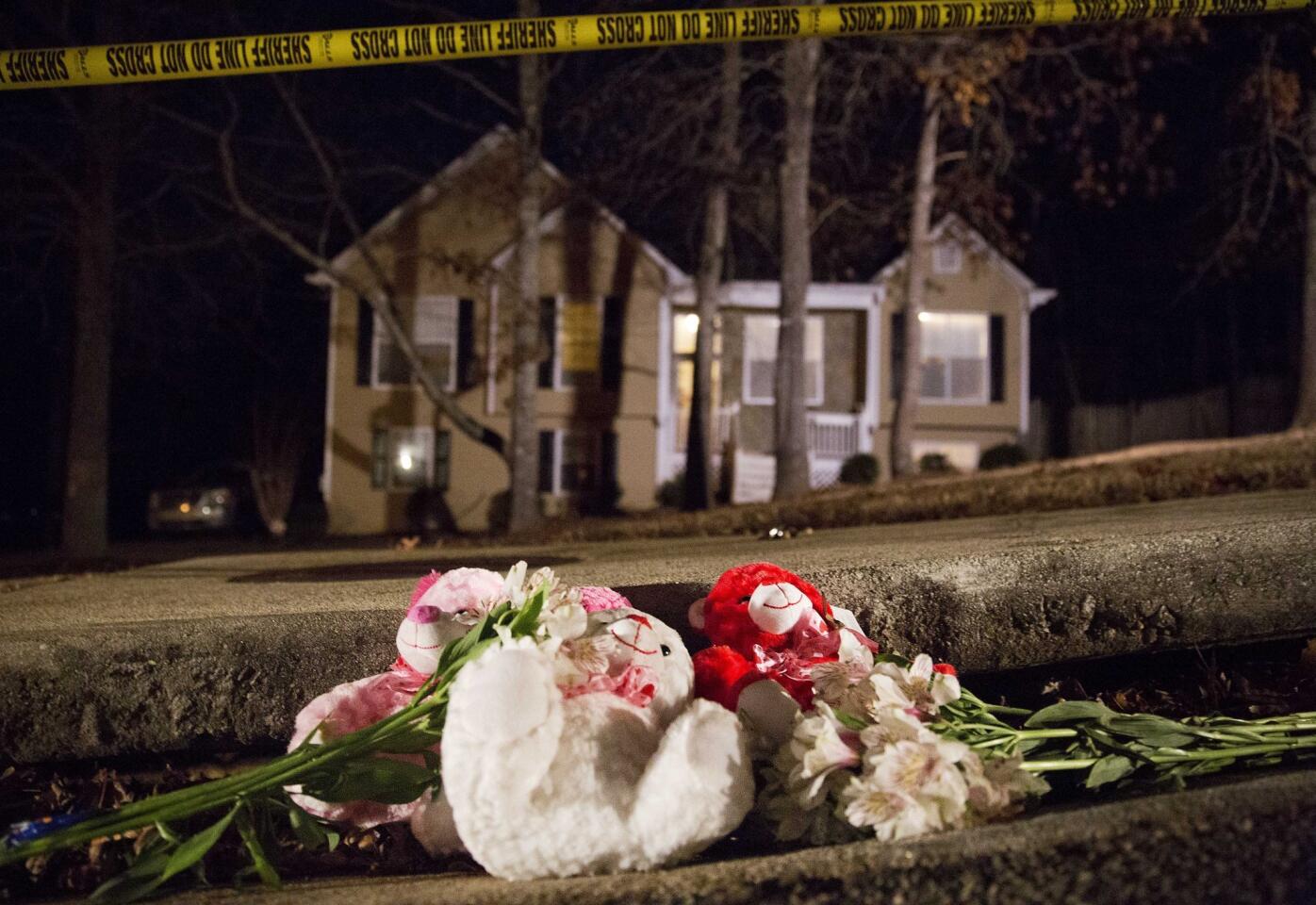 Flowers and teddy bears lay on the street outside the home of a shooting scene where authorities say five people are dead, including the gunman, in Douglasville, Ga. on Saturday, Feb. 7, 2015. Douglas County Sheriff's Lt. Glenn Daniel said the gunman shot six people before fatally shooting himself, and the two surviving victims are children, but children are also among the dead.