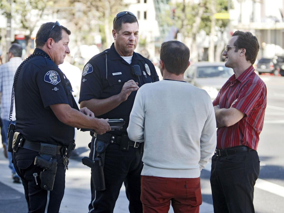 These two men who ran diagonally across at Brand and Americana Way got a ticket for crossing on a solid red hand during Glendale Police Dept. pedestrian violations enforcement operation in Glendale on Thursday, Nov. 14, 2013. GPD officer Lindner, left, and Frommling, second from left, explain the rules of crossing the street to the violators.