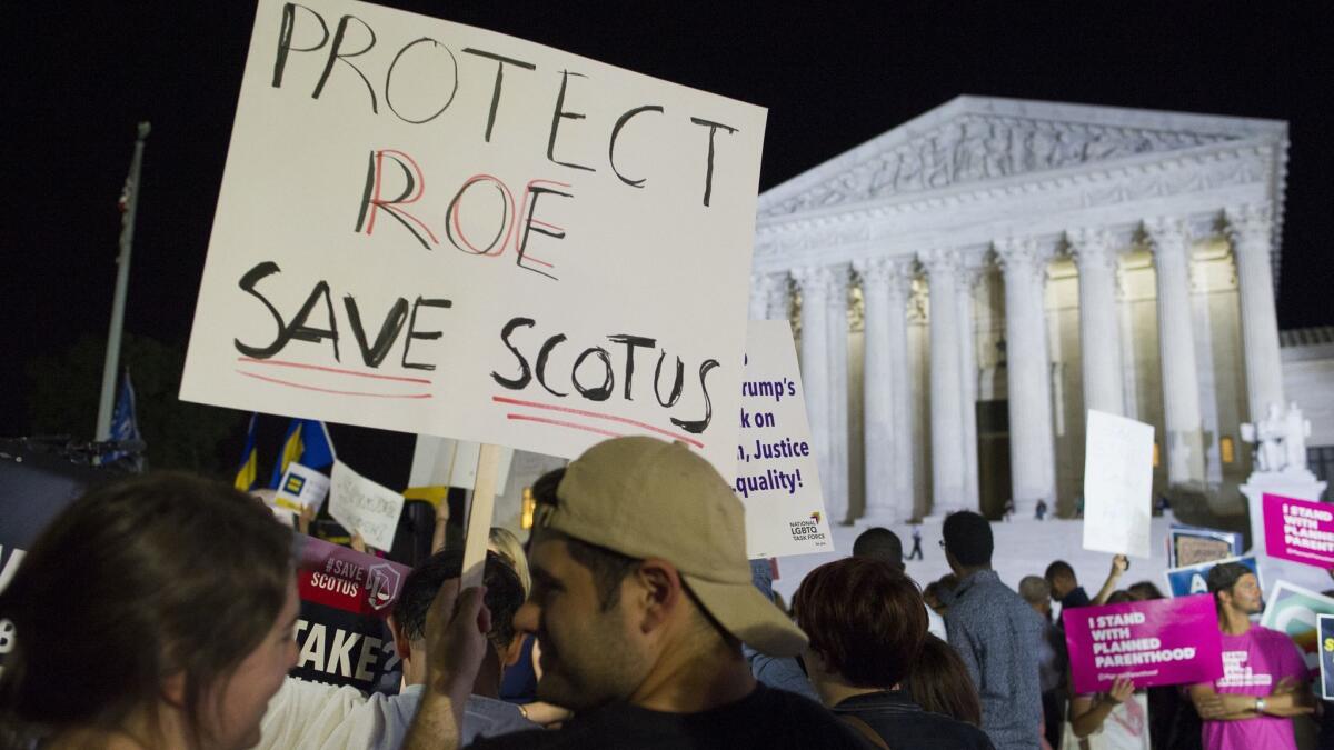 Demonstrators hold signs outside the Supreme Court on July 9 after President Trump announced his nomination of Brett Kavanaugh to the high court.