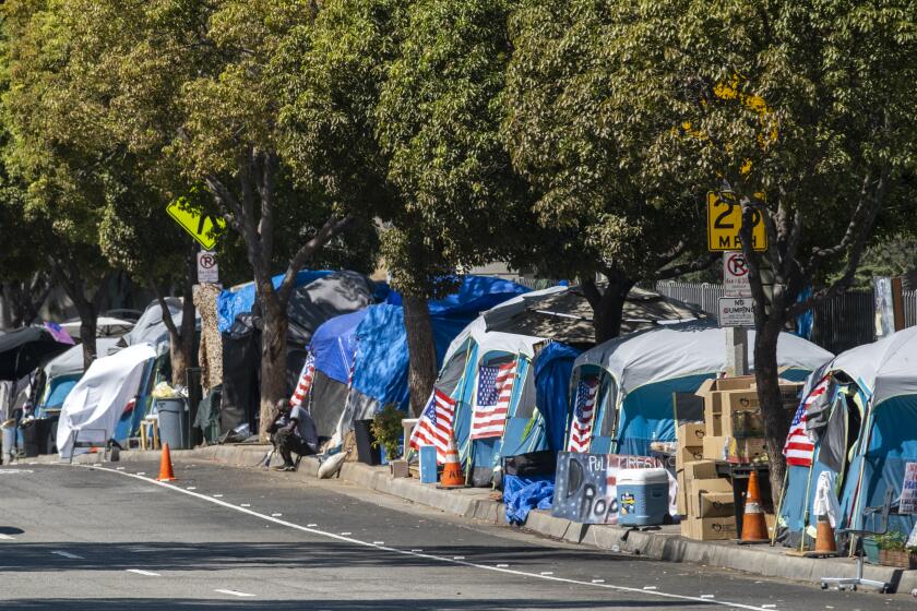 WEST LOS ANGELES, CA - AUGUST 30: A homeless encampment outside the West L.A. Veterans Affairs facilities on Monday, Aug. 30, 2021. The encampment is on San Vicente Boulevard in an unincorporated area near Brentwood in West Los Angeles, CA. Dozens of veterans live at the encampment, sometimes called Veterans Row, where some tents are decorated with U.S. flags. Recently a homeless veteran had been stapped to death near by. (Francine Orr / Los Angeles Times)