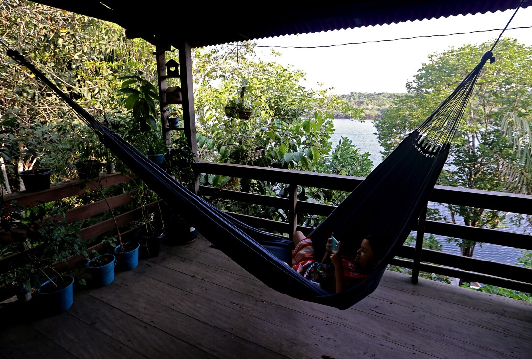 A child plays video games while swinging in a hammock