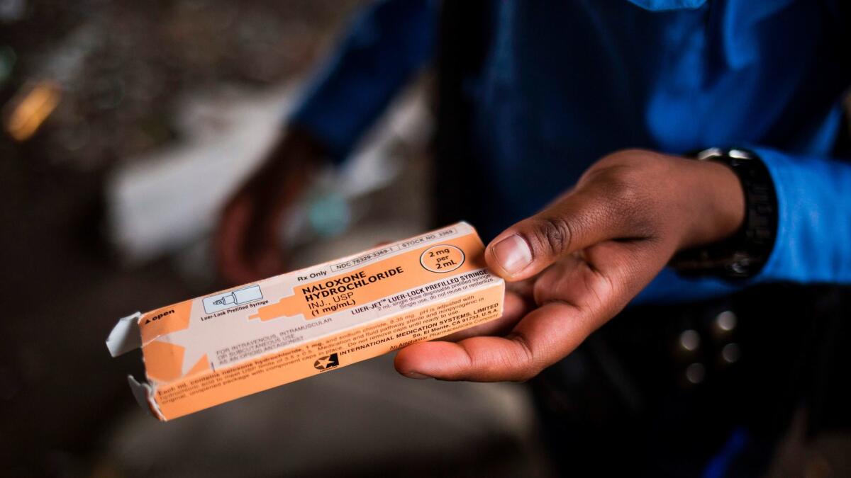 A Philadelphia police officer holds a package of the overdose reversal agent naloxone hydrochloride, which is sold under the brand name Narcan. A new report urges "universal access" to addiction treatment.