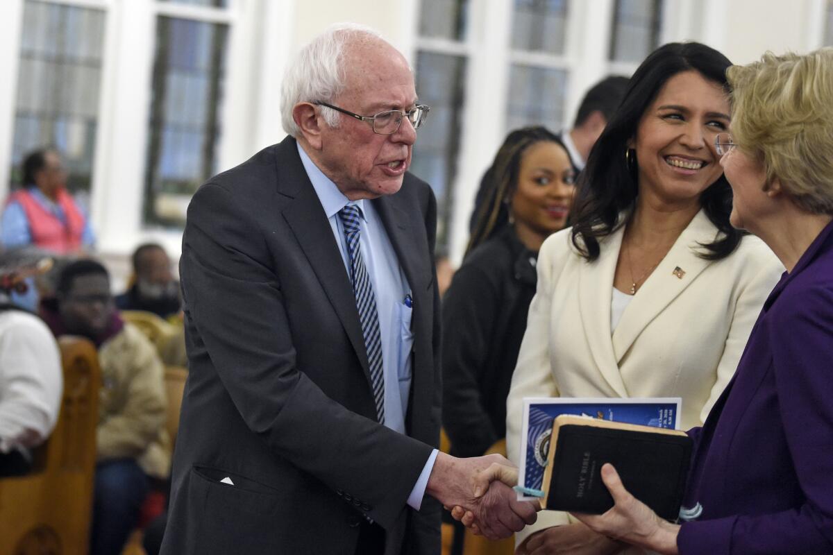 Democratic presidential candidates Sens. Bernie Sanders and Elizabeth Warren shake hands Monday in Columbia, S.C. Rep. Tulsi Gabbard (D-Hawaii) is center.