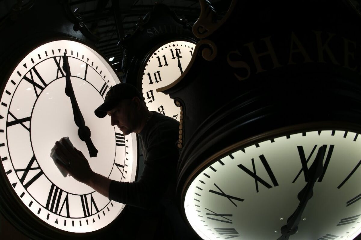 Dave LeMote wipes down a clock at Electric Time Co. in Medfield, Mass., on Friday. Most Americans will set their clocks 60 minutes forward before heading to bed Saturday night.