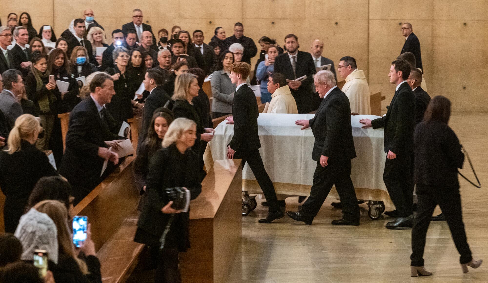 Relatives of the bishop walk with the casket after the vigil Mass