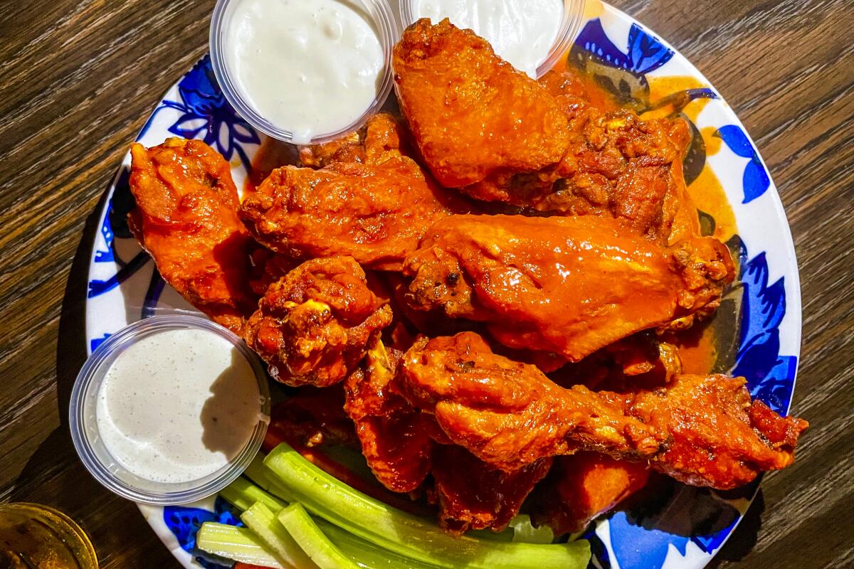 A plate of Buffalo chicken wings with blue cheese dip and celery sticks.