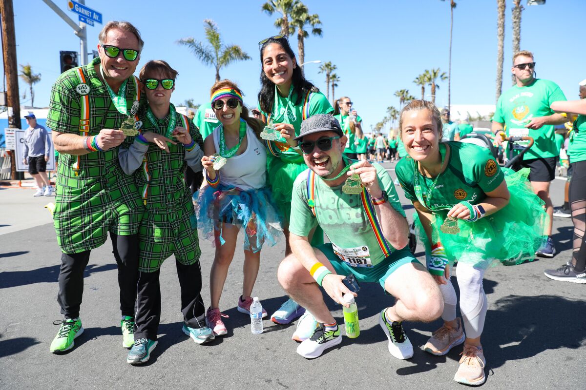 Leprechaun Run participants holding up their medals at the finish line.