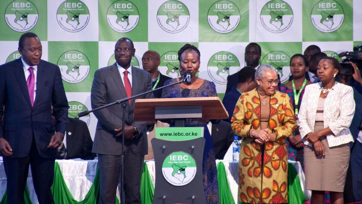 Kenyan electoral official Roselyn Akombe, center, speaks as President Uhuru Kenyatta, left, prepares to receive his electoral win certificate, later nullified in Nairobi, Kenya. Akombe resigned Oct. 18 and fled the country after receiving threats.
