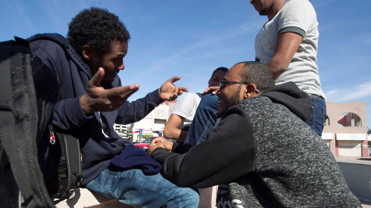 Mesfin Tesfaldet, 33, left, of Eritrea talks with other asylum seekers in a commercial plaza near the pedestrian crossing.