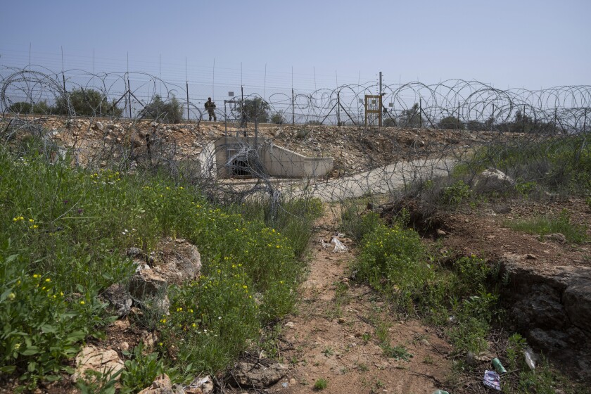 An Israeli soldier guards an opening in Israel's West Bank separation barrier that was reinforced with barbed wire to prevent Palestinians from crossing into Israel, in the West Bank village of Nilin, west of Ramallah, Sunday, April 10, 2022. Israel has stepped up its surveillance of the barrier following a pair of attacks in recent weeks carried out by Palestinians who had entered Israel without a permit. (AP Photo/Nasser Nasser)