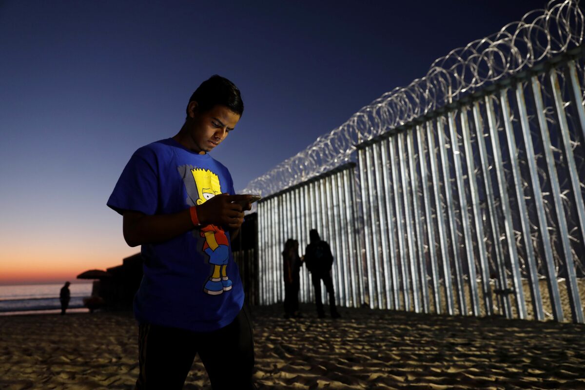 Honduran Jorge Sevilla, 20,checks his phone at Playas Tijuana along the U.S. - Mexico border in Tijuana. Sevilla is not sure if he will seek political asylum or cross illegally into San Diego.