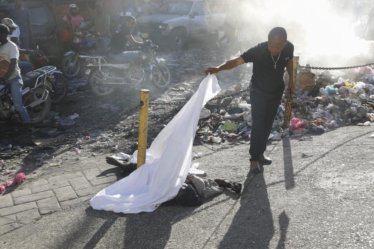 Una persona levanta la sábana que cubría un cadáver en el vecindario Petion Ville de Puerto Príncipe
