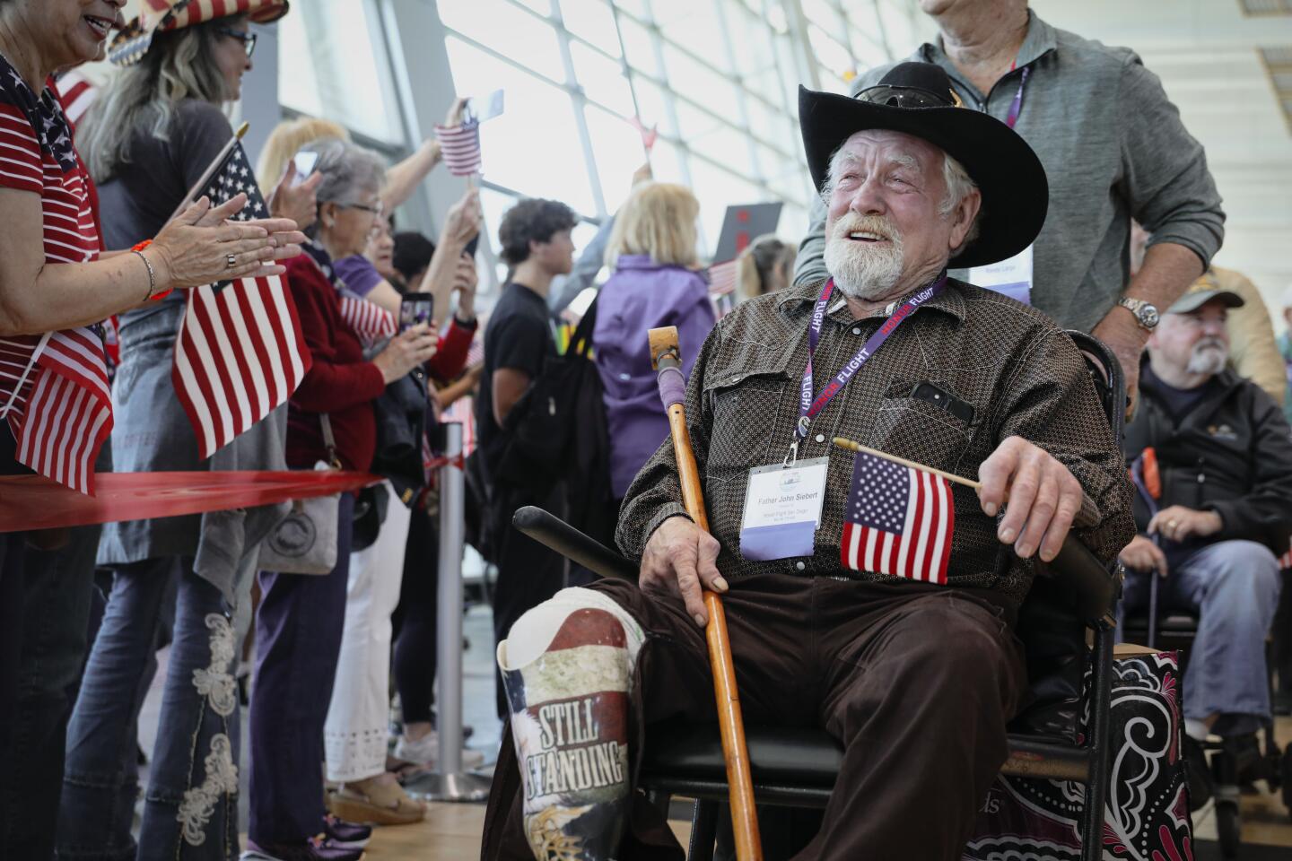 Navy Veteran Father John Siebert greets supporters after arriving back in San Diego from an Honor Flight tour, at the San Diego International Airport on Sunday, April 28, 2024.