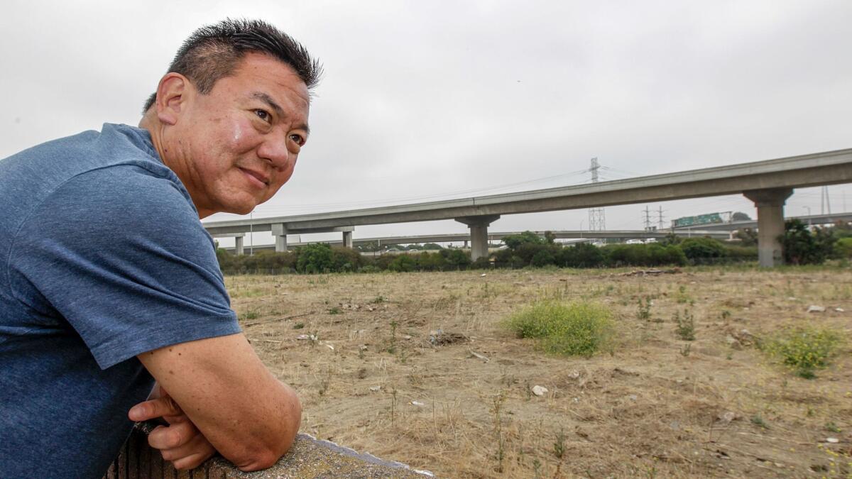 Harbor Gateway resident Craig Kusunoki looks from his backyard wall onto the site of a proposed 15-home subdivision planned near the interchange of the 110 and 91 Freeways. Opponents say future residents will face noise and air pollution from nearby cars and trucks. (Irfan Khan / Los Angeles Times)