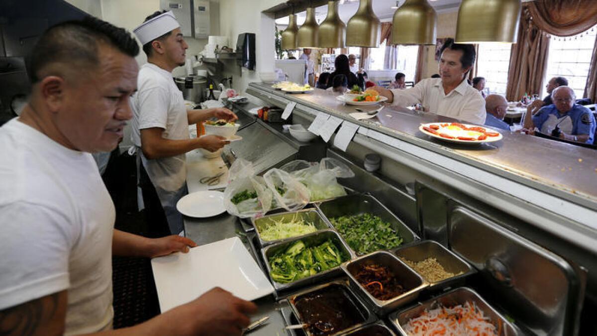 Roberto Torres, a la derecha, recoge las comidas preparadas por el chef Juan Ramírez, izquierda, y Omar Reynoso.