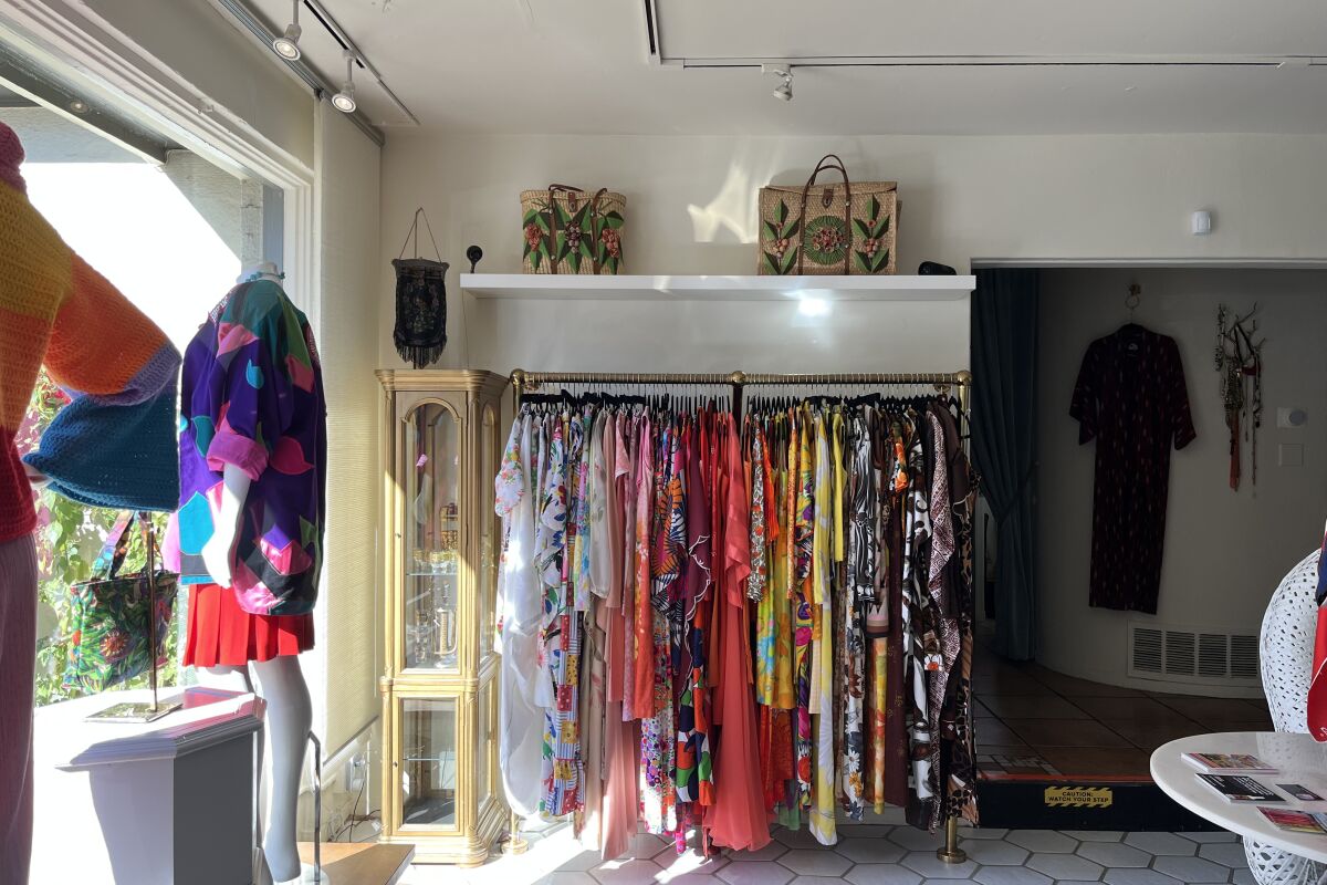 A rack of colorful caftans and dresses inside a store.
