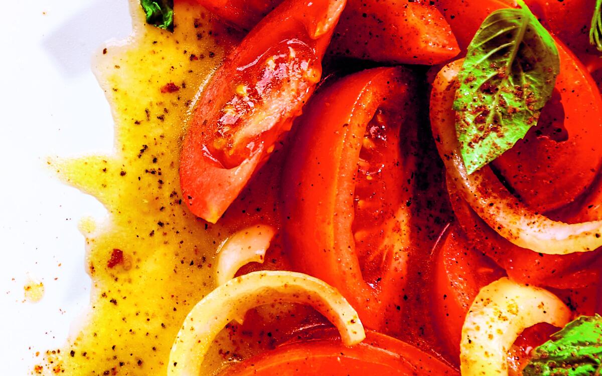 Sliced tomatoes and onions with basil and dressing flecked with chili flakes and cayenne