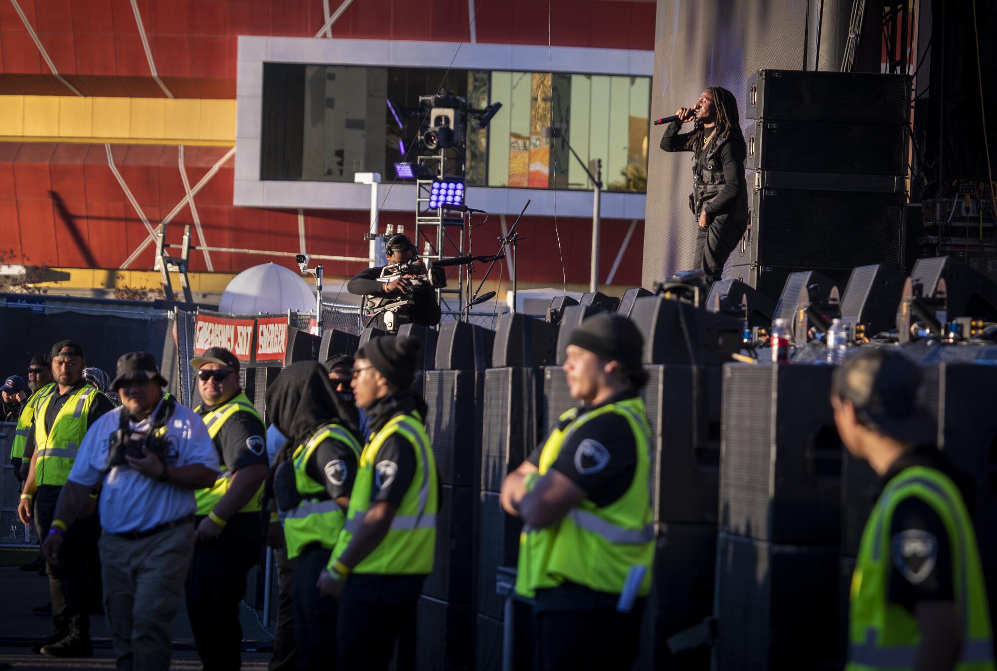 Security stands in front of the stage and watches the crowd as D Smoke performs on stage above.