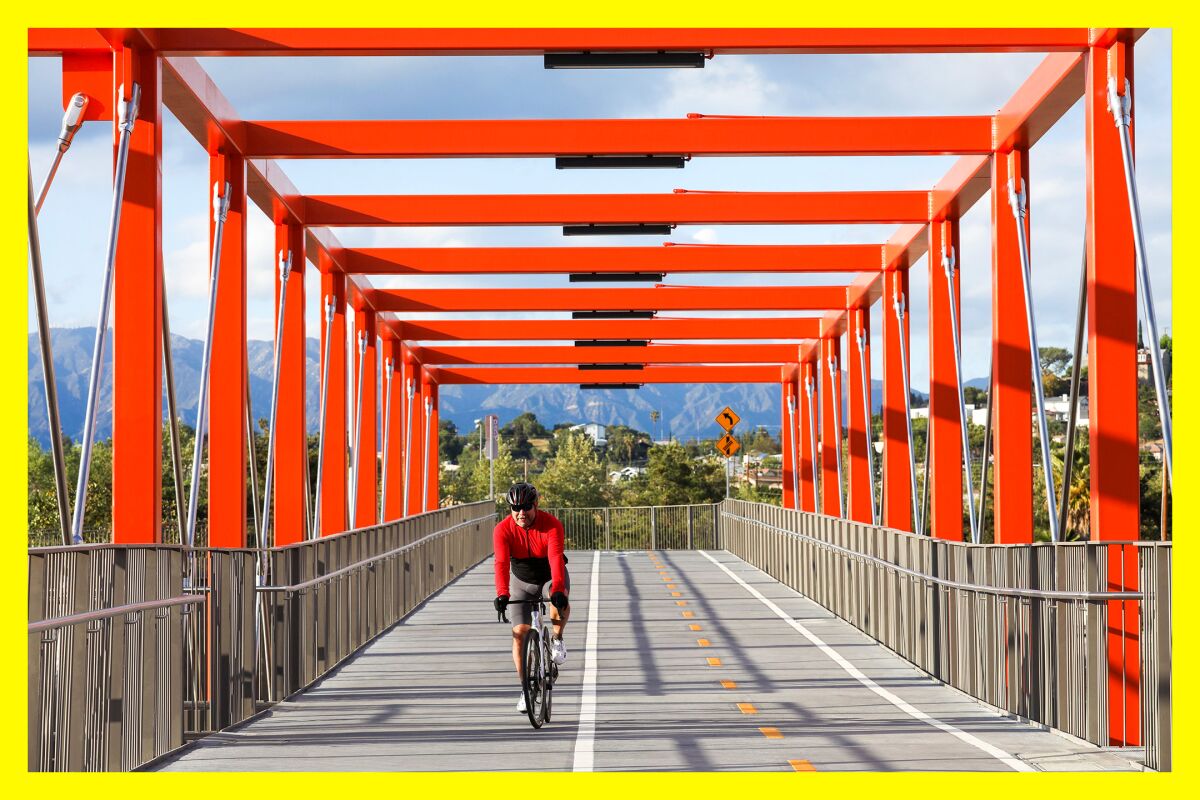 A man in a red cycling shirt rides his bike across the Taylor Yard Bridge over the Los Angeles River.