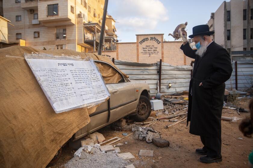 An ultra-Orthodox Jewish man, wearing a face mask during a nationwide three-week lockdown to curb the spread of the coronavirus, swings a chicken over his head as part of the Kaparot ritual, in Bnei Brak, Israel, Wednesday, Sept 23, 2020. Observant Jews believe the ritual transfers one's sins from the past year into the chicken, and is performed before the Day of Atonement, Yom Kippur, the holiest day in the Jewish year which starts at sundown Sunday. (AP Photo/Oded Balilty)