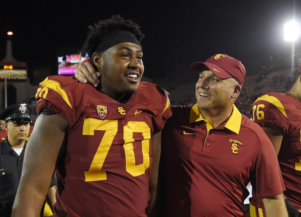USC interim Coach Clay Helton, right, puts his arm around offensive tackle Chuma Edoga after the Trojans defeated Utah on Oct. 24.