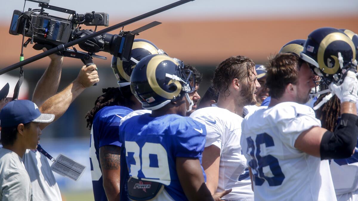 "Hard Knocks" crew members lift a camera and boom mic above Rams players during a workout at UC Irvine on Aug. 1.