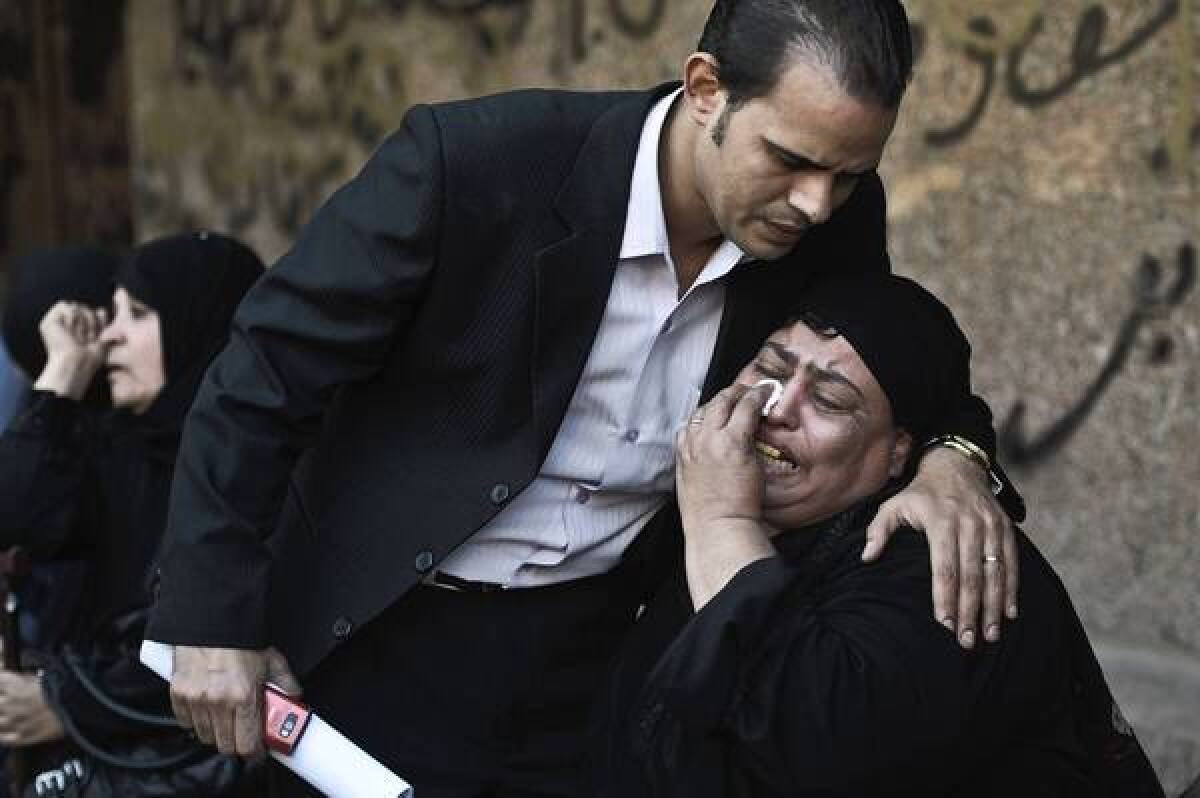 A relative of one of the victims of a shooting at a Coptic Christian Church in Cairo is comforted as she mourns at a morgue.