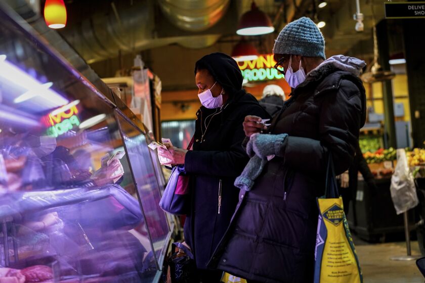 Customers wearing face masks to protect against the spread of the coronavirus shop at the Reading Terminal Market in Philadelphia, Wednesday, Feb. 16, 2022. Philadelphia city officials lifted the city's vaccine mandate for indoor dining and other establishments that serve food and drinks, but an indoor mask mandate remains in place. Philadelphia Public Health officials announced that the vaccine mandate was lifted immediately Wednesday. (AP Photo/Matt Rourke)