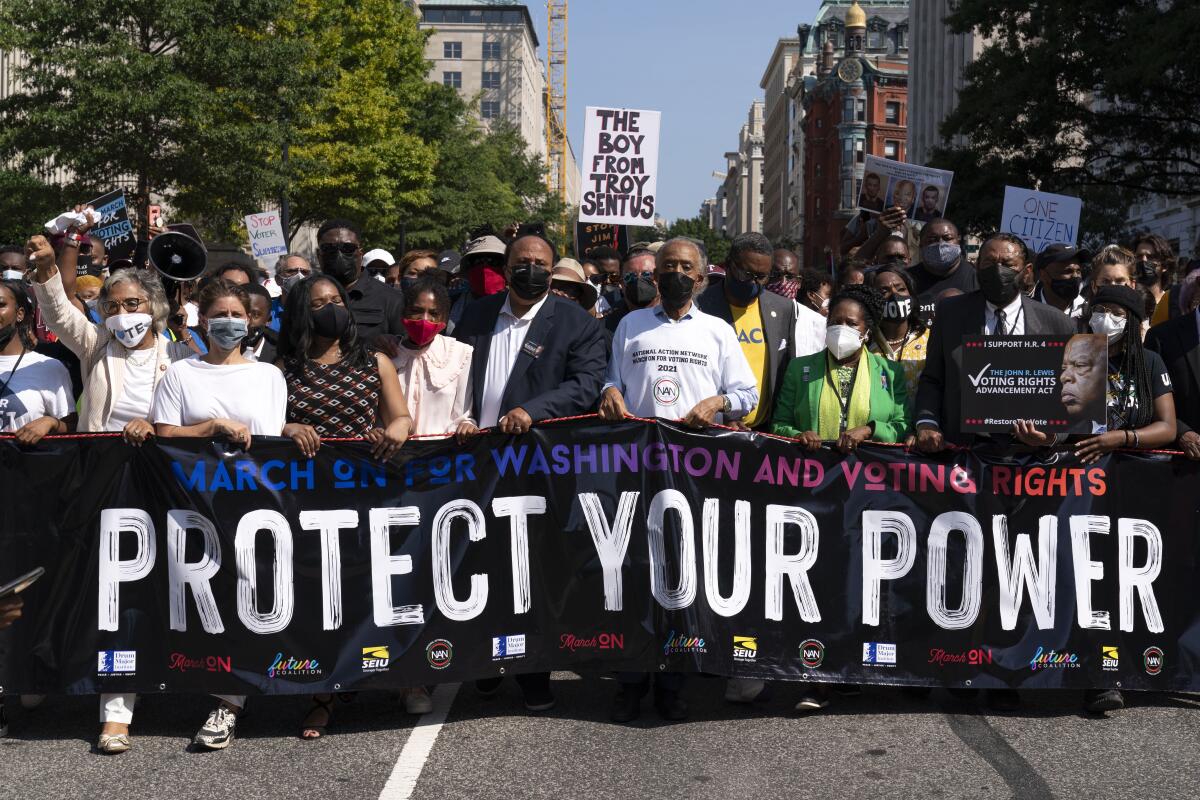 Marchers carry a sign reading "Protect your power."